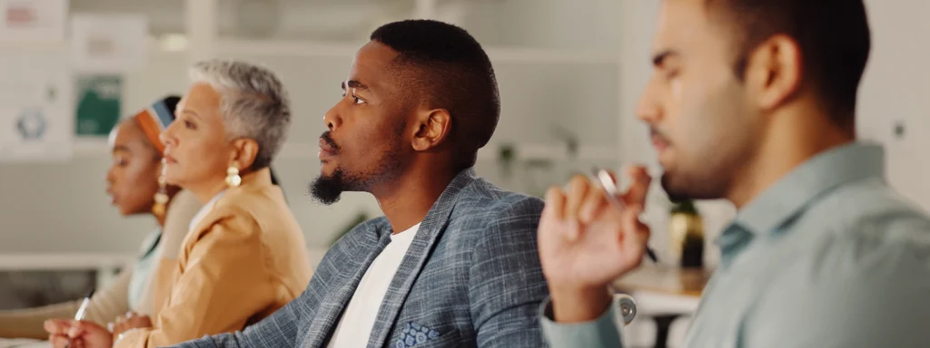 people sitting at table looking ahead one person in focus